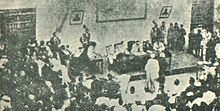 محاكمة عمر المختار. يظهر المختار في وسط الصورة (صاحب الرداء الأبيض) مُقابل قوس القضاة.